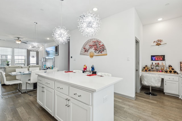 kitchen featuring white cabinets, light countertops, wood finished floors, and a kitchen island