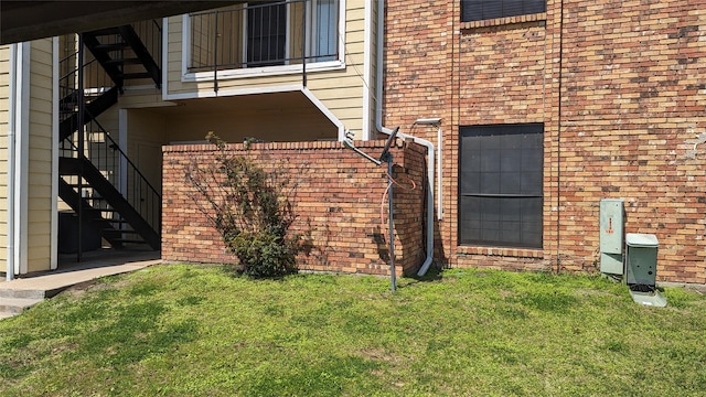 exterior space featuring a yard, stairs, and brick siding