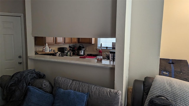 interior space with a peninsula, light countertops, brown cabinetry, and open floor plan