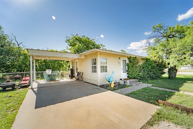 view of front of home featuring fence, outdoor dining area, a patio, a fire pit, and a front yard