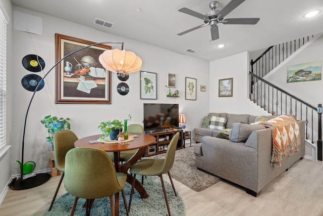 living room with a ceiling fan, stairs, visible vents, and light wood-type flooring