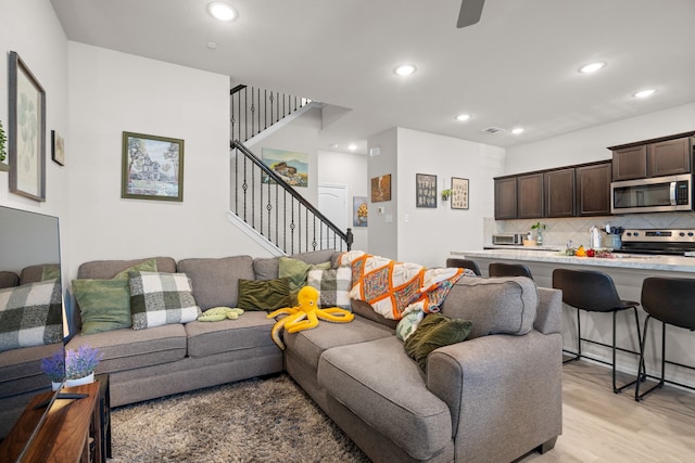 living area featuring recessed lighting, light wood-style floors, and stairway