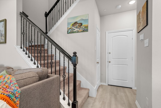 foyer entrance featuring baseboards, wood finished floors, recessed lighting, and stairs
