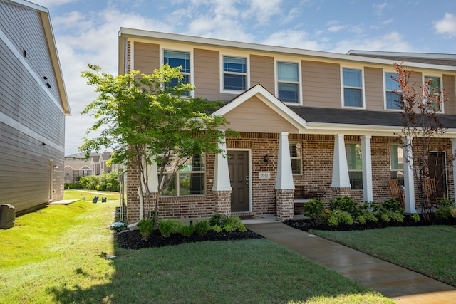 view of front of property with a front lawn, brick siding, and a porch