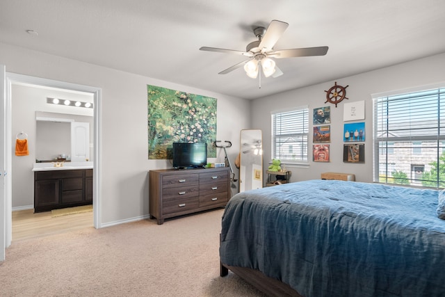 bedroom featuring baseboards, ensuite bath, a ceiling fan, and light colored carpet