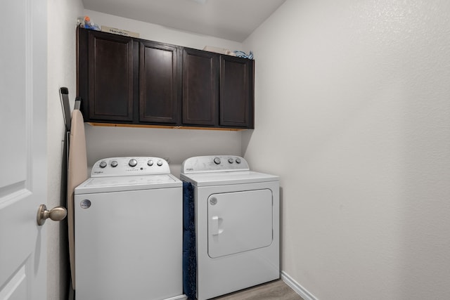 washroom featuring cabinet space, light wood-style floors, washing machine and clothes dryer, and baseboards
