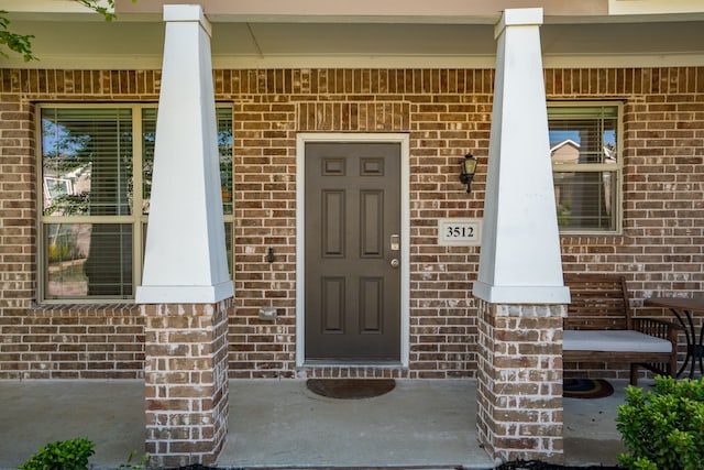 entrance to property with brick siding and a porch