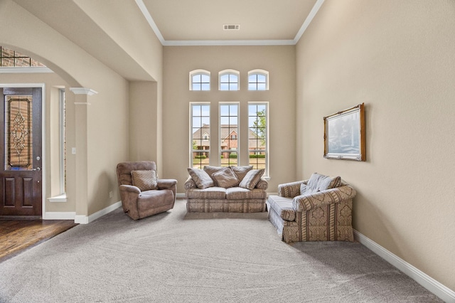 sitting room featuring visible vents, arched walkways, carpet floors, baseboards, and ornamental molding