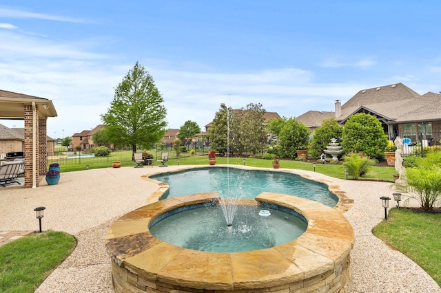 pool with a lawn, a patio, an in ground hot tub, and fence