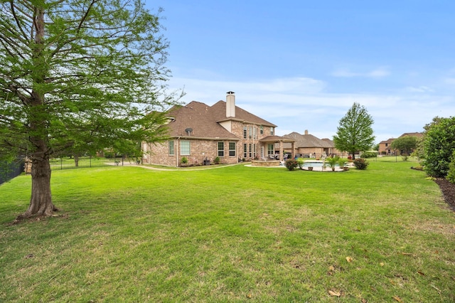 rear view of property featuring a lawn, fence, a chimney, and an outdoor pool