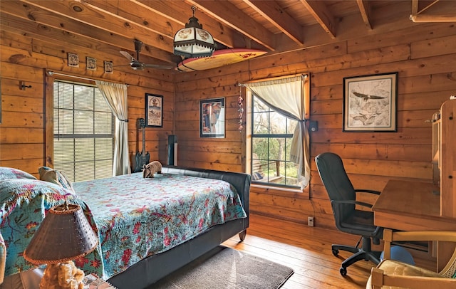 bedroom featuring wooden walls, hardwood / wood-style flooring, and multiple windows