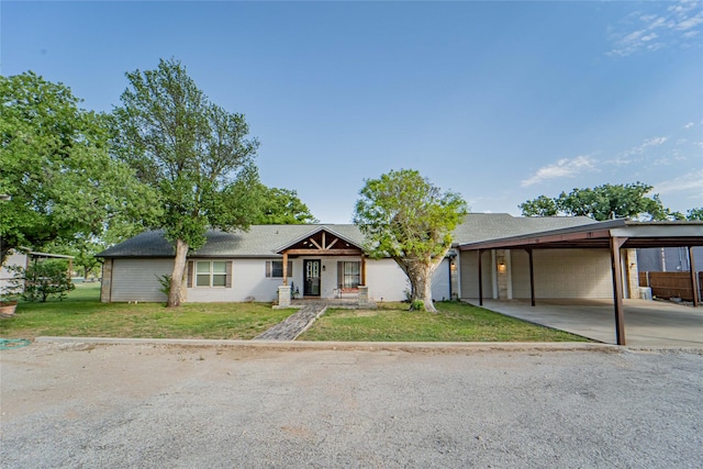ranch-style home featuring driveway, a shingled roof, a front lawn, and an attached carport
