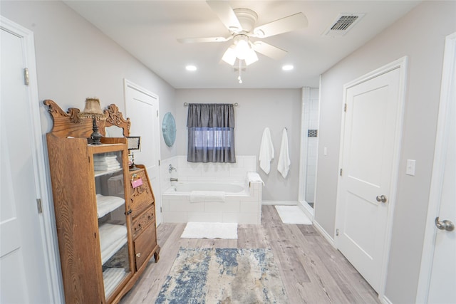 bathroom with visible vents, a ceiling fan, wood finished floors, a shower stall, and a garden tub