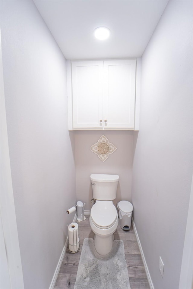 bathroom with baseboards, wood finished floors, and toilet