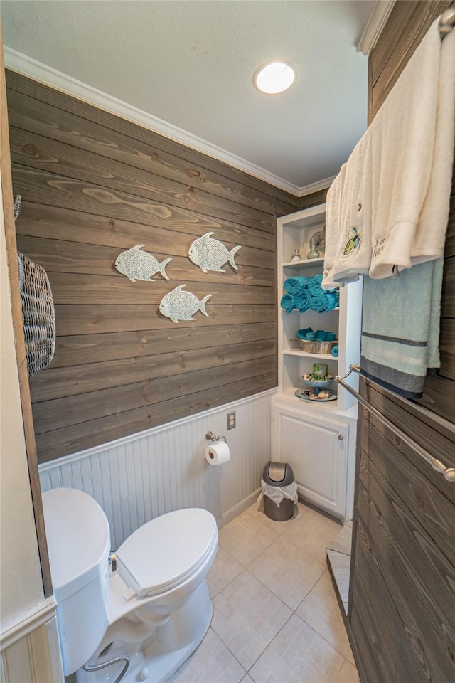 bathroom featuring wood walls, tile patterned flooring, ornamental molding, and toilet