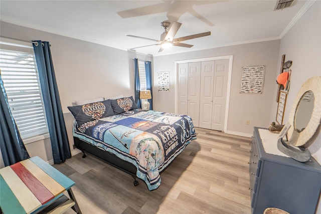 bedroom with light wood-type flooring, baseboards, visible vents, a closet, and ornamental molding