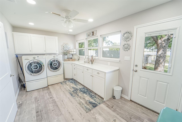 clothes washing area with cabinet space, light wood-style floors, washing machine and dryer, and a healthy amount of sunlight