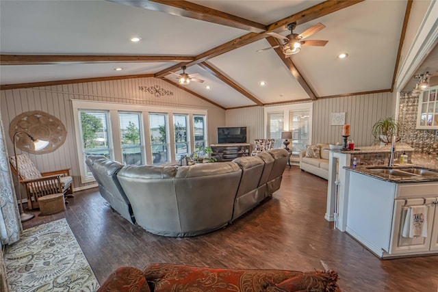 living area with vaulted ceiling with beams, a ceiling fan, a wealth of natural light, and dark wood-type flooring