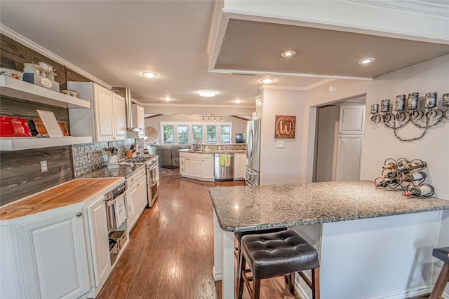 kitchen featuring a peninsula, crown molding, stainless steel appliances, and a breakfast bar area