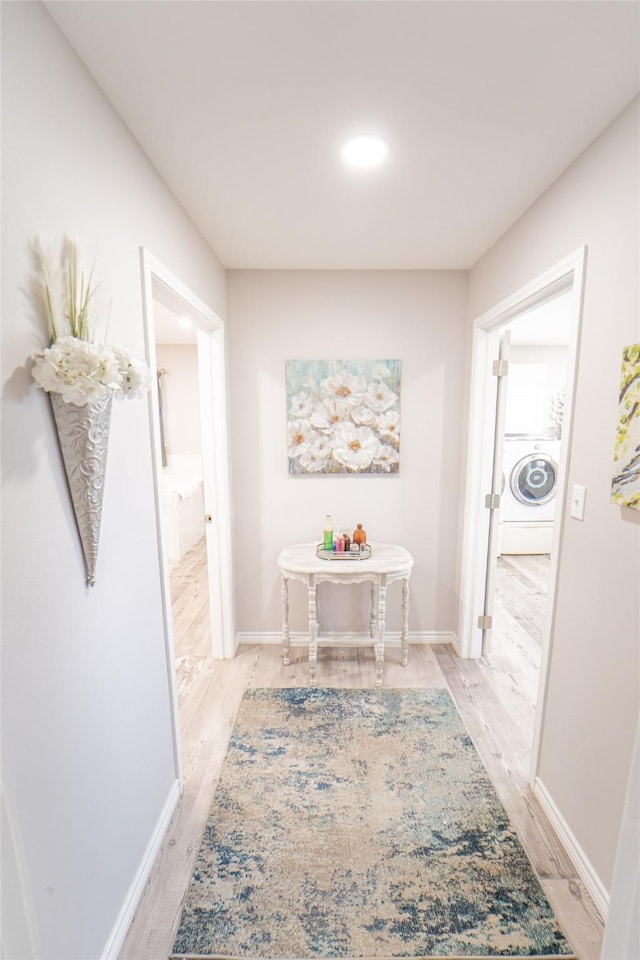 hallway with washer / dryer, light wood finished floors, and baseboards