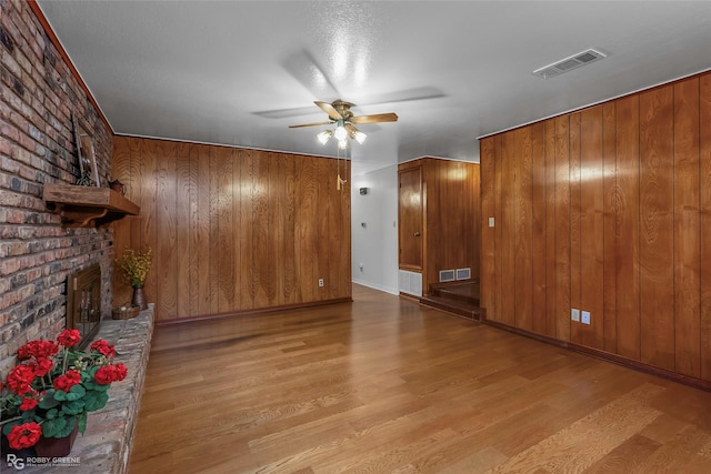2007 Venus Dr, Bossier City, LA 71112 - unfurnished living room with visible vents, ceiling fan, wooden walls, wood finished floors, and a fireplace