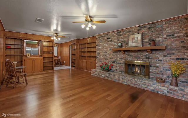 2007 Venus Dr, Bossier City, LA 71112 - unfurnished living room with wood finished floors, a fireplace, visible vents, ceiling fan, and wooden walls