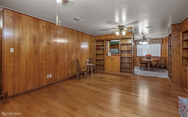 2007 Venus Dr, Bossier City, LA 71112 - living area featuring wood walls, a ceiling fan, visible vents, and wood finished floors