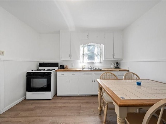 211 S Smyth St, Mart, TX 76664 - kitchen featuring light wood finished floors, gas range, white cabinetry, and a sink