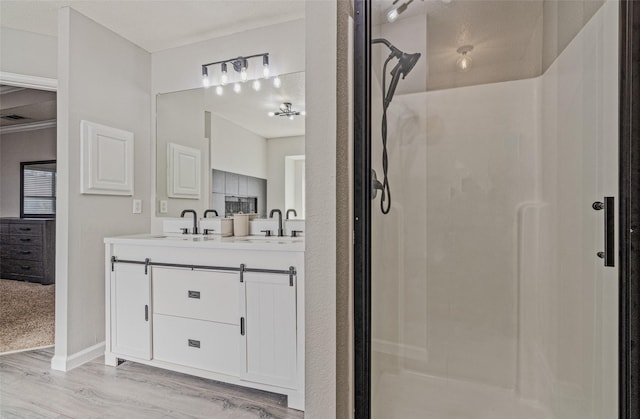 139 Wembley Way, Rockwall, TX 75032 - full bathroom featuring double vanity, wood finished floors, a stall shower, and a sink