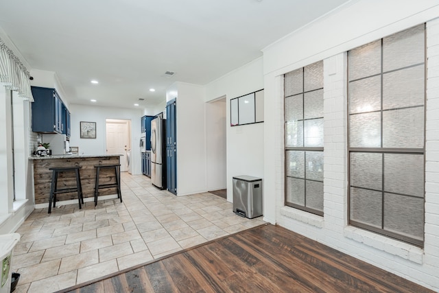 kitchen with light wood finished floors, a kitchen breakfast bar, visible vents, freestanding refrigerator, and blue cabinetry
