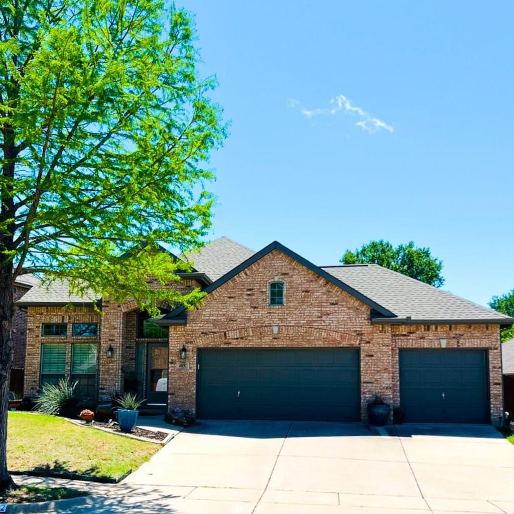 view of front of house featuring brick siding, an attached garage, a shingled roof, and driveway
