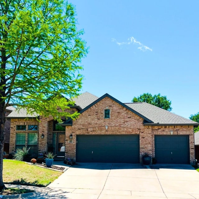 view of front of house featuring brick siding, an attached garage, a shingled roof, and driveway