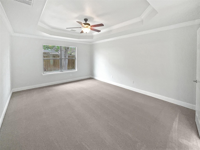 unfurnished room featuring a raised ceiling, carpet floors, and a ceiling fan
