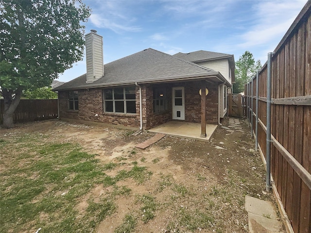 back of house featuring a patio area, a fenced backyard, a chimney, and brick siding