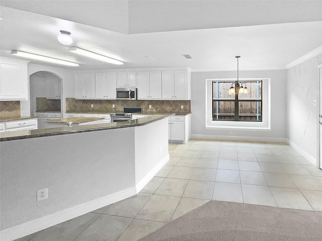 kitchen featuring white cabinets, stainless steel appliances, arched walkways, and backsplash