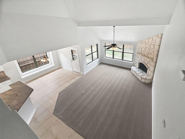 unfurnished living room with tile patterned floors, a stone fireplace, a ceiling fan, baseboards, and lofted ceiling with beams