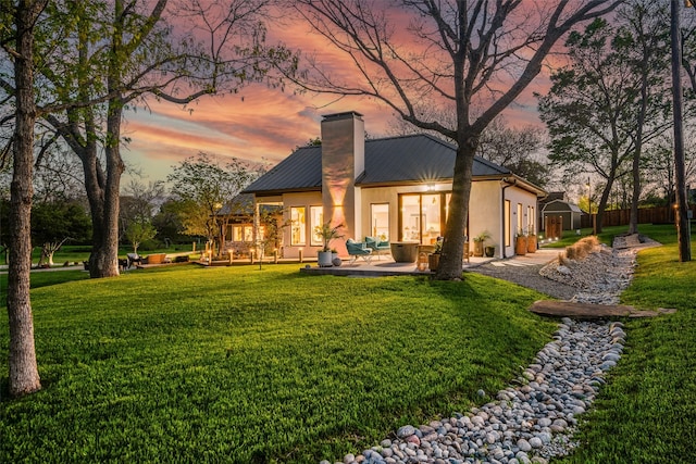 3485 Stonewall Rd, Wylie, TX 75098 - back of property at dusk featuring fence, a patio, a chimney, metal roof, and a lawn