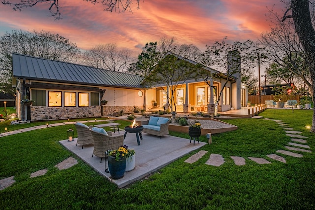 3485 Stonewall Rd, Wylie, TX 75098 - rear view of house with an outdoor living space with a fire pit, a yard, stone siding, and a standing seam roof