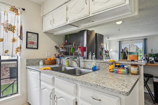 911 Turtle Lake Blvd, Irving, TX 75060 - kitchen featuring a sink, dishwasher, light countertops, white cabinets, and a peninsula