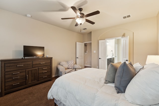 bedroom featuring connected bathroom, dark carpet, a ceiling fan, baseboards, and visible vents