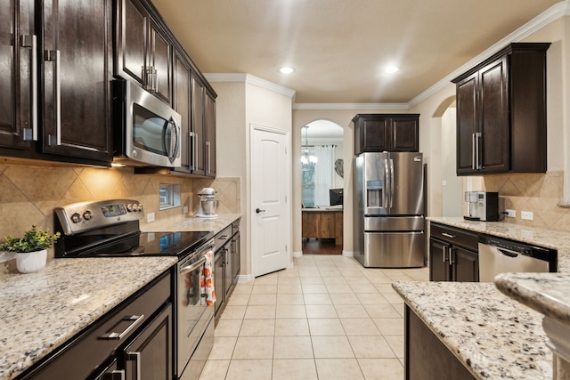kitchen with crown molding, appliances with stainless steel finishes, arched walkways, dark brown cabinets, and light tile patterned floors