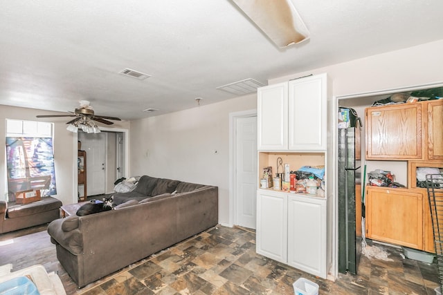 living area featuring stone finish flooring, ceiling fan, and visible vents