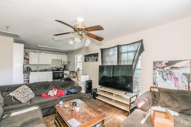 living area with a ceiling fan, wood finished floors, and visible vents