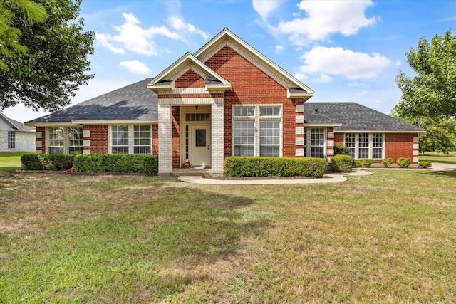 view of front of property with brick siding, roof with shingles, and a front lawn
