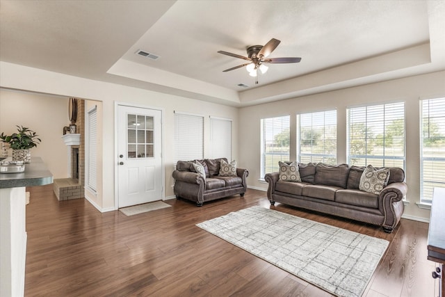 living room with a tray ceiling, a healthy amount of sunlight, and a ceiling fan