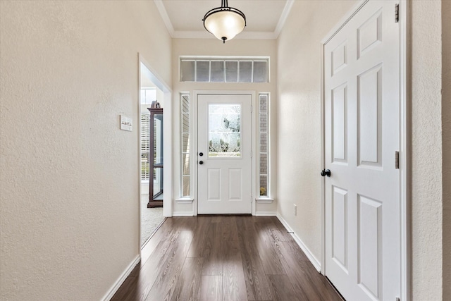 foyer with dark wood-style floors, a textured wall, visible vents, ornamental molding, and baseboards