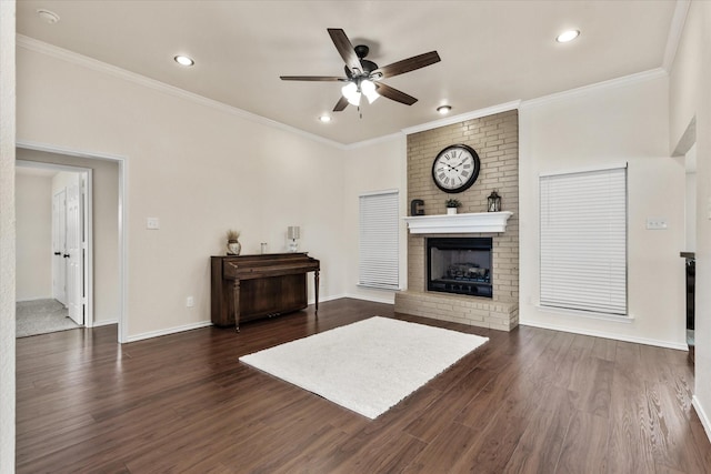 living area with ornamental molding, a ceiling fan, a brick fireplace, and dark wood-type flooring