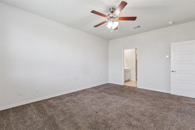 unfurnished bedroom featuring light carpet, ensuite bathroom, baseboards, visible vents, and ceiling fan