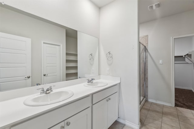 bathroom with double vanity, a shower stall, tile patterned floors, and a sink