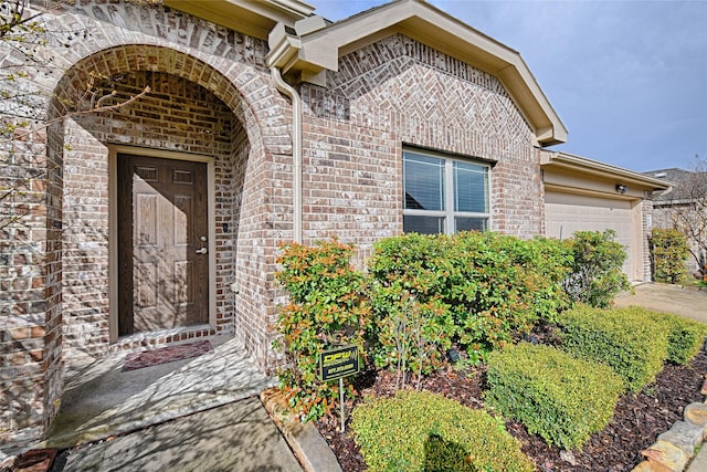 doorway to property with a garage and brick siding